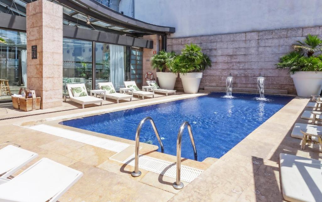 马德里Hotel Urban,a Member of Design Hotels的一座带躺椅的游泳池位于大楼旁