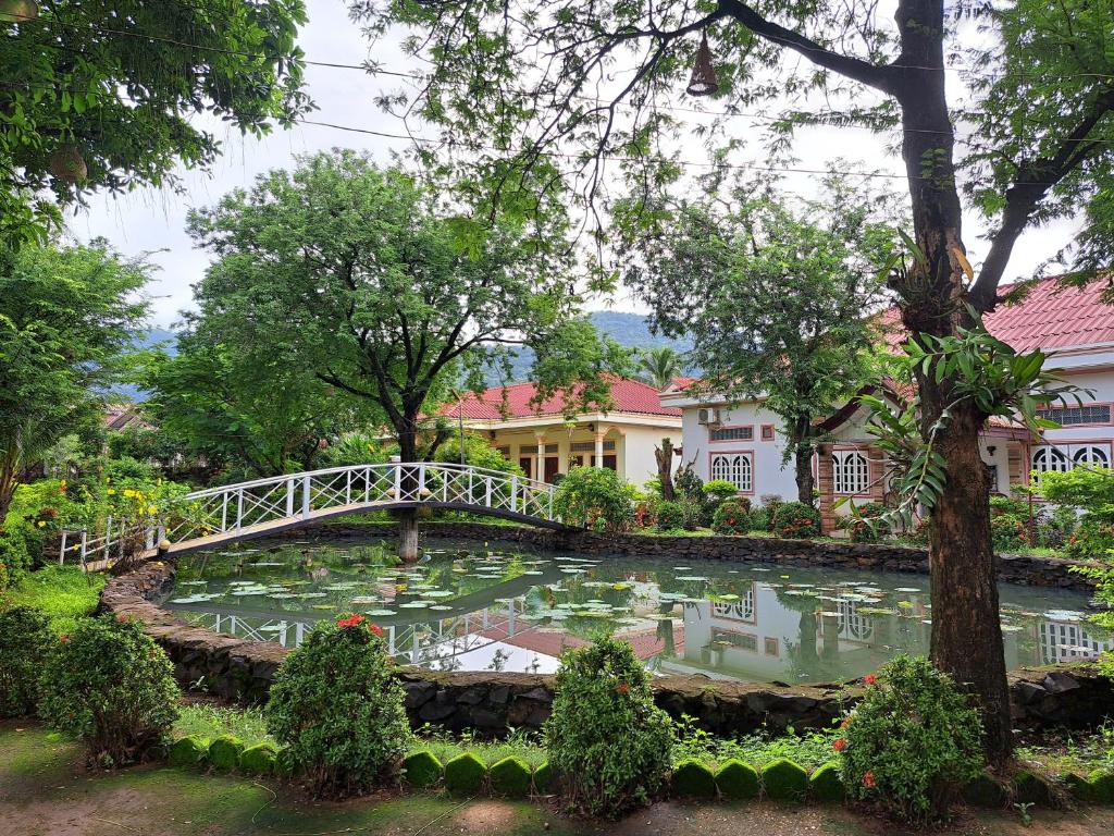 巴色宣迈花园度假旅馆的一座桥在一座建筑前面的池塘上
