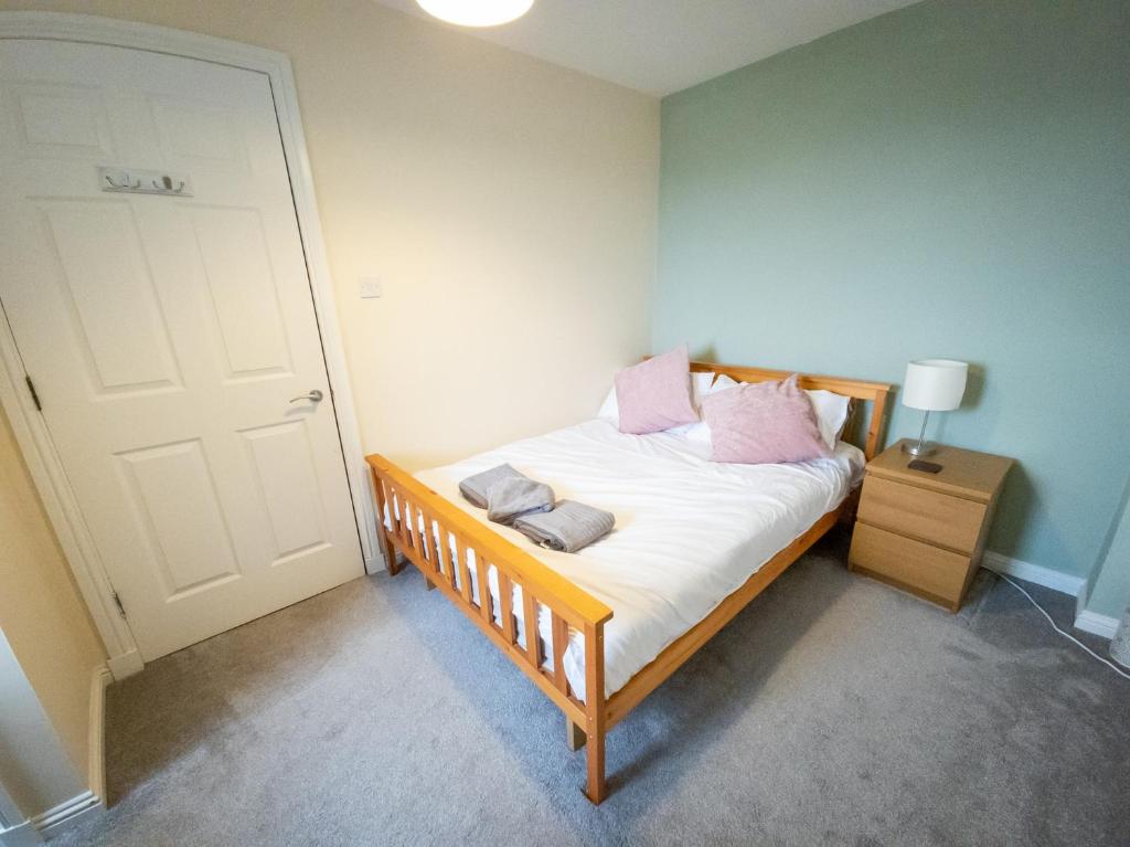 福尔柯克Tranquil 2Bed/2Bath Duplex Falkirk的一间卧室配有带白色床单和粉红色枕头的床。