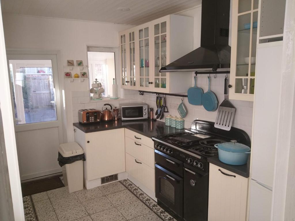 滨海戈尔斯顿Gorgeous Gorleston holiday home的厨房配有白色橱柜和黑炉灶烤箱。