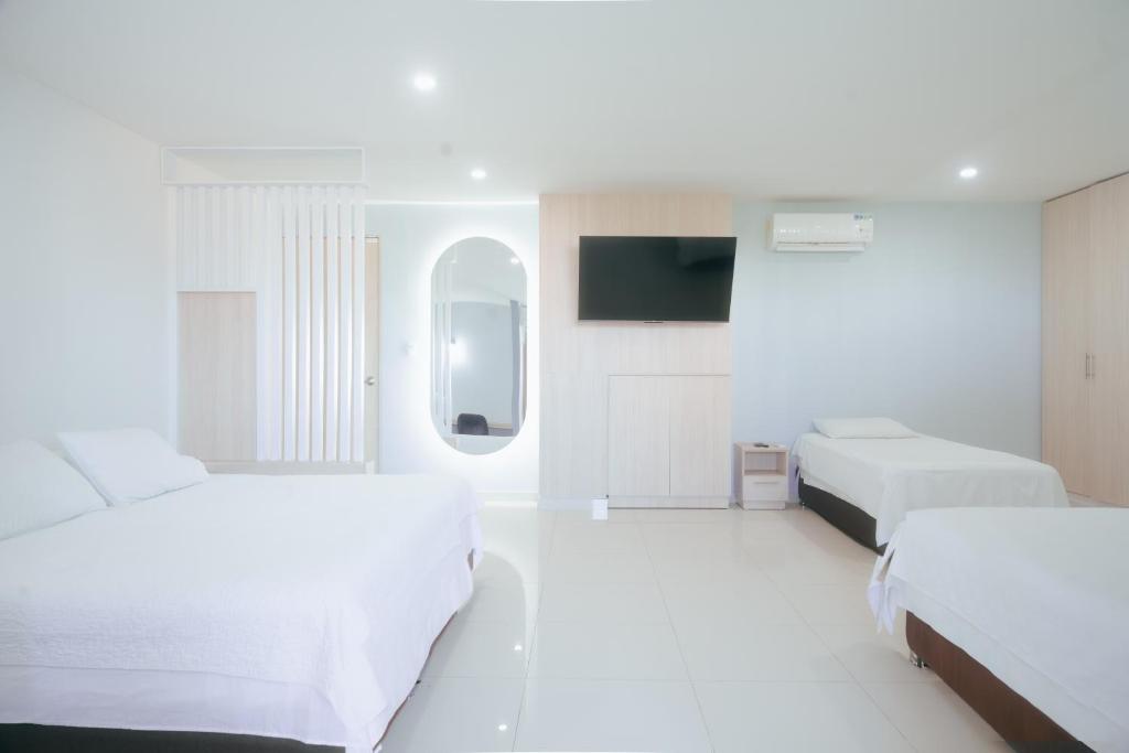 巴兰基亚Apartaestudios lagos的白色的客房配有两张床和电视。