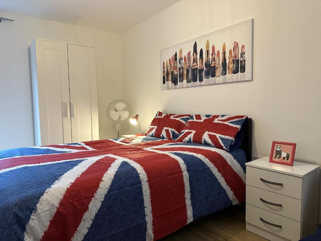 伦敦Modern, Large Independent Room with En-suite Bathroom in Private Owned Apartment的一间卧室配有红色的白色和蓝色的床和床头柜