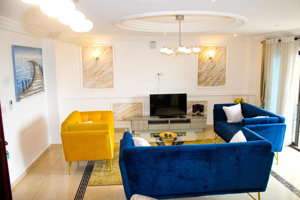 杜阿拉Residence Le Carat Bonapriso的客厅配有蓝色的沙发和黄色的椅子