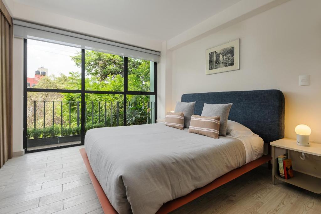 墨西哥城Choapan 28 - Lux Apartments in Condesa的一间卧室设有一张大床和一个大窗户