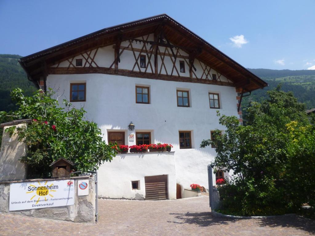 马莱斯韦诺斯塔Sonnenheimhof的一座白色的大建筑,上面有红色的花朵