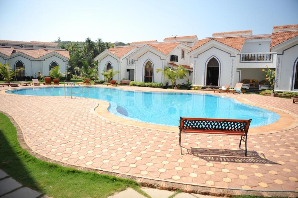 阿伯来Riviera Hermitage Goa的房屋前带长凳的游泳池