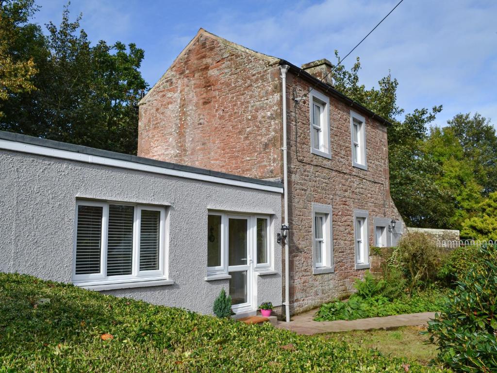 BlencogoBlaithwaite Cottage的一座带白色窗户和庭院的老砖屋