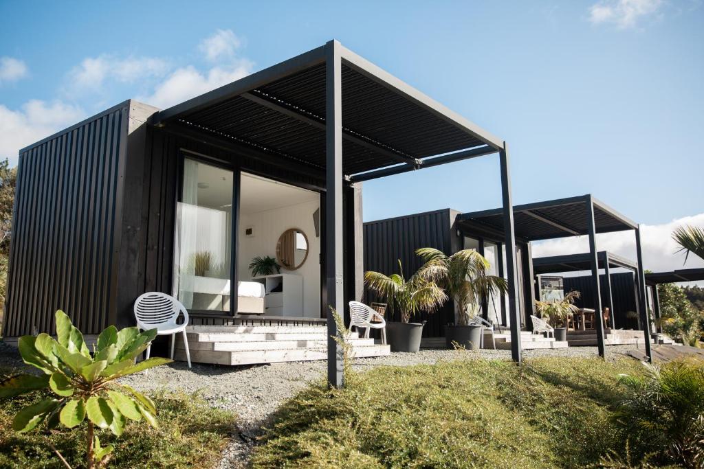 Te AraiAotearoa Surf Eco Pods的黑色房子,有黑色屋顶