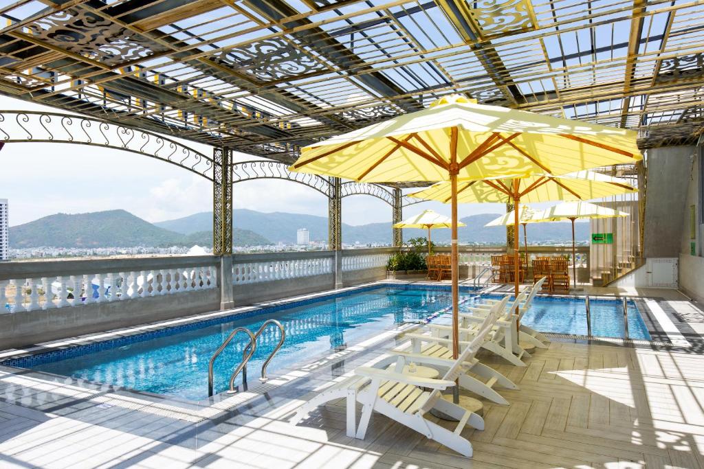 归仁Pearl Beach Hotel Quy Nhon的大楼内一个带椅子和遮阳伞的游泳池