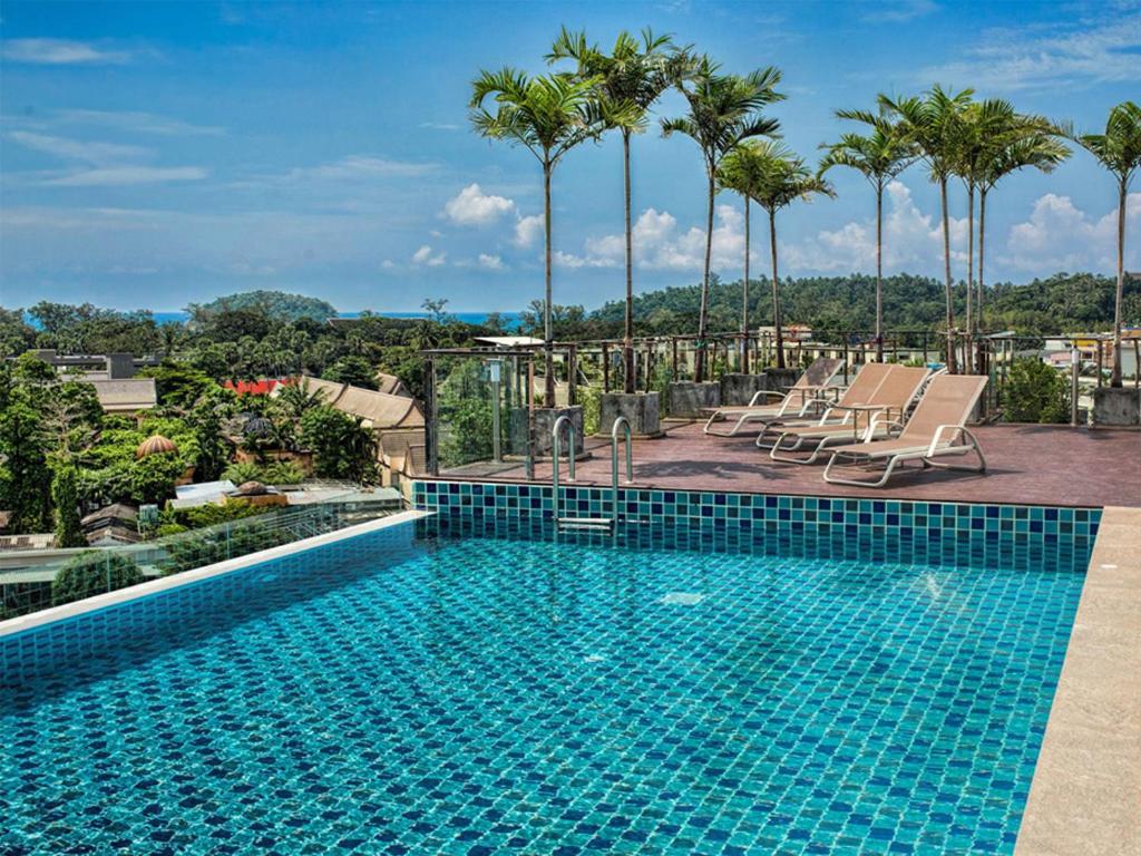 卡塔海滩Superbe Studio avec Salle De Bain Privee Kata Beach Phuket Phuket的棕榈树建筑顶部的游泳池