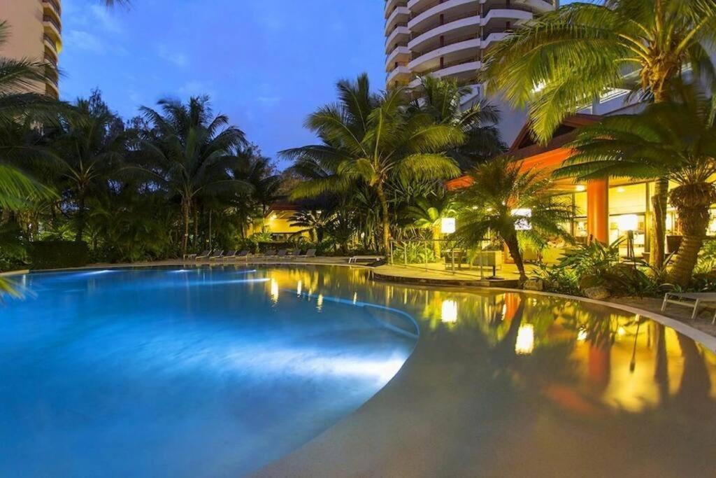 努美阿Appartement F3 sur l'anse vata, bord de mer的一座棕榈树和建筑的大型游泳池