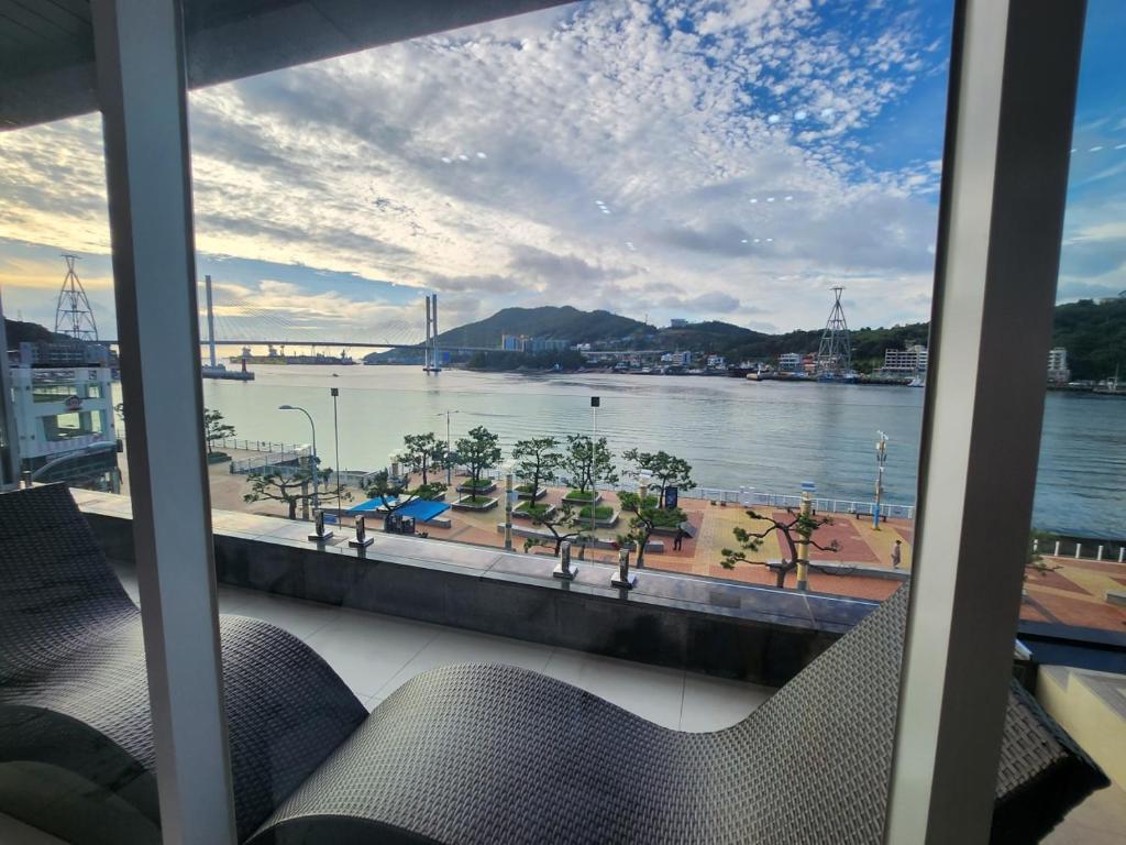 丽水市Suite Stay Yeosu的窗户享有水景,配有椅子