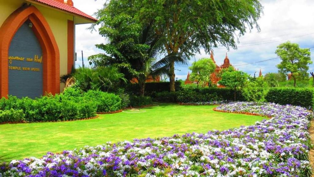 蒲甘Myanmar Nan Hteik Temple View Hotel的一座花园,在一座建筑前种有紫色花卉