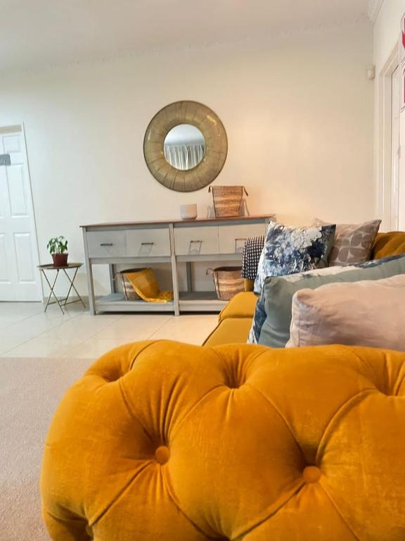 弗朗西斯敦Ambré Guesthouse的客厅配有黄色沙发和镜子