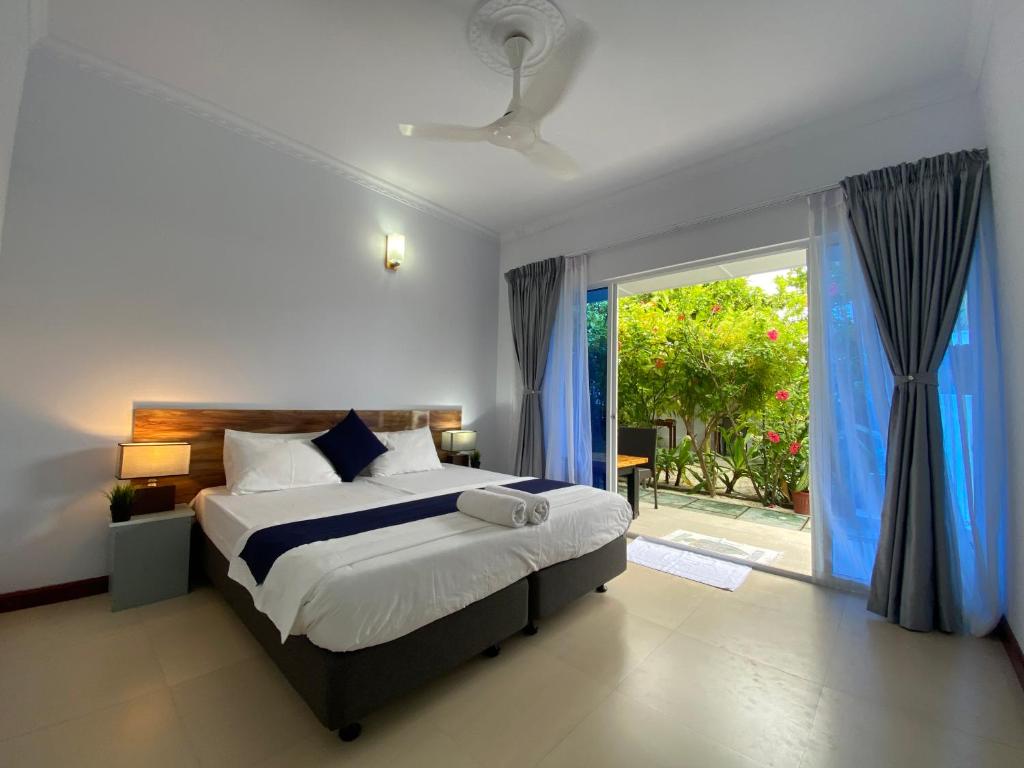 迪古拉Tides Dhigurah的一间卧室设有一张床和一个滑动玻璃门