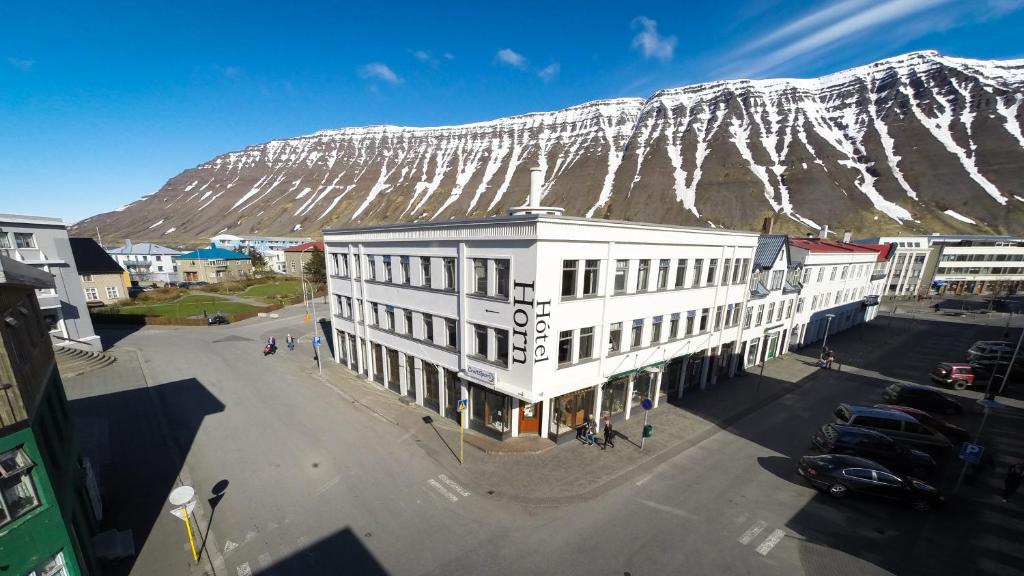 伊萨菲尔德Hotel Isafjordur - Horn的一座白楼,底下有雪覆盖的山