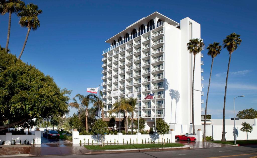 洛杉矶Cameo Beverly Hills的一间大型的白色酒店,前面有棕榈树