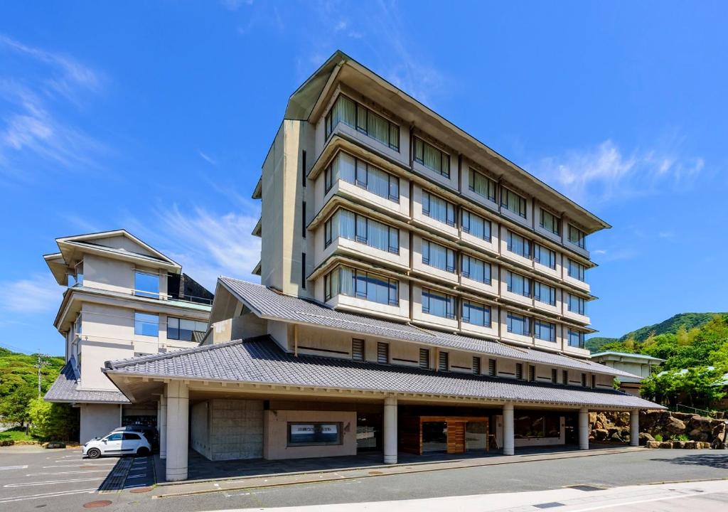 下关Kawatana Grand Hotel Otafuku的一座高大的建筑,前面有一辆汽车