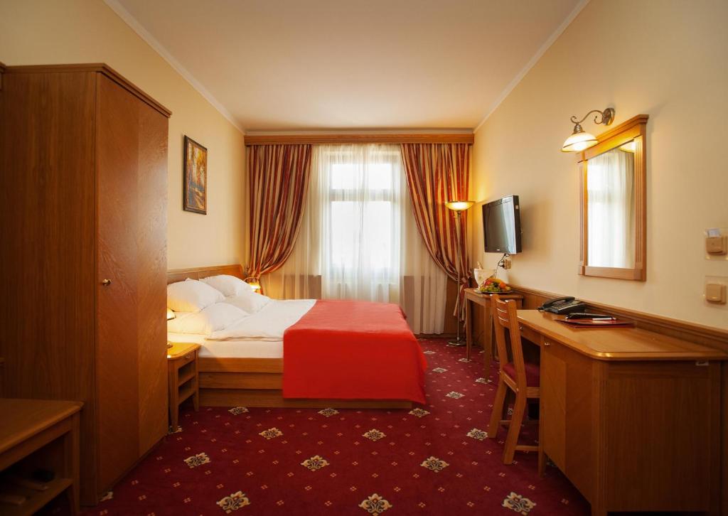 布拉格阿斯卡尼亚酒店的配有一张床和一张书桌的酒店客房