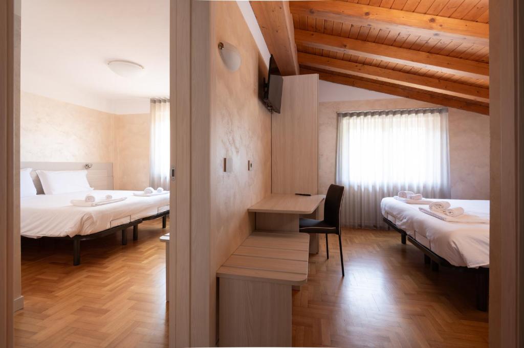韦扎多廖Hotel Vezza Alpine Lodge & Spa的客房设有两张床和一张桌子及椅子