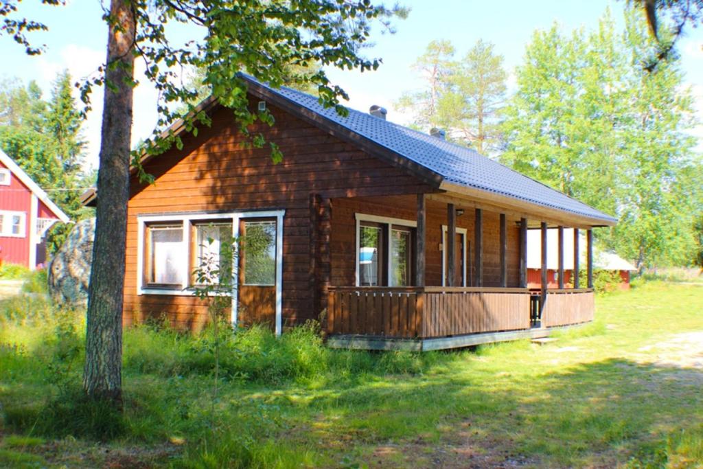 BlattnikseleSandsjögården Holiday Resort的田野上的小木房子,有树