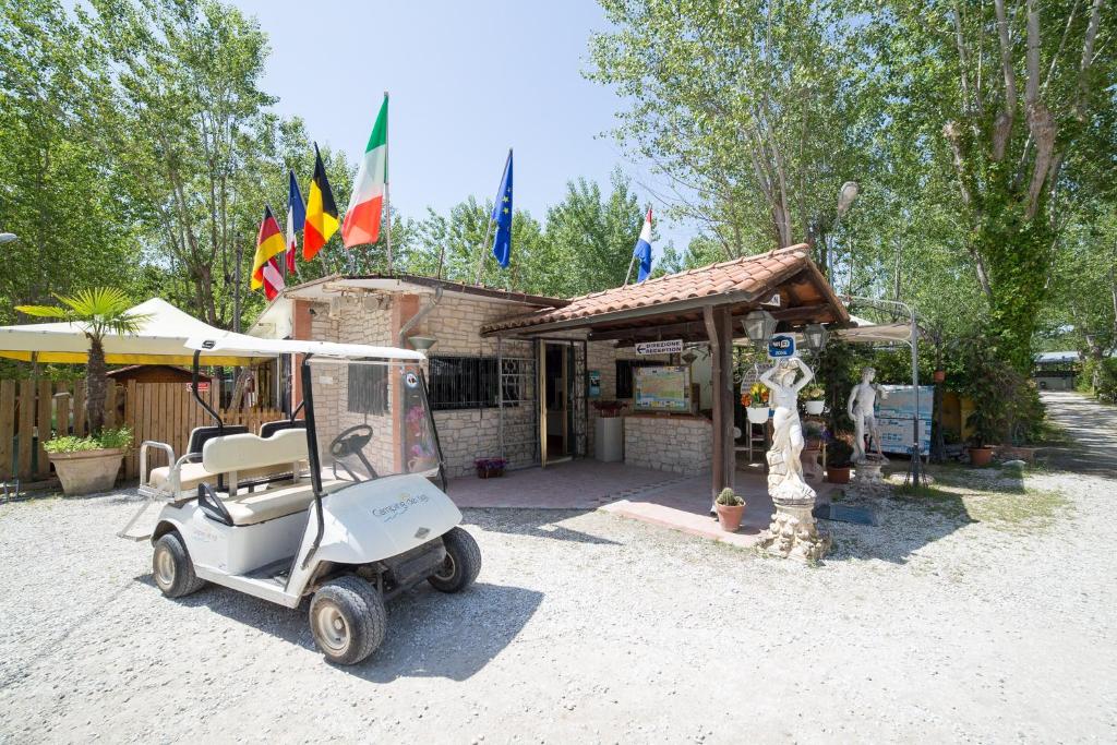 托雷德尔格拉戈普奇Camping dei Tigli的停在有旗帜的建筑前的高尔夫球车