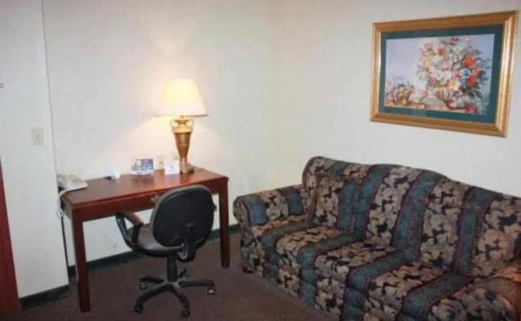 琼斯伯勒Ark Suites的酒店客房配有沙发、书桌和椅子