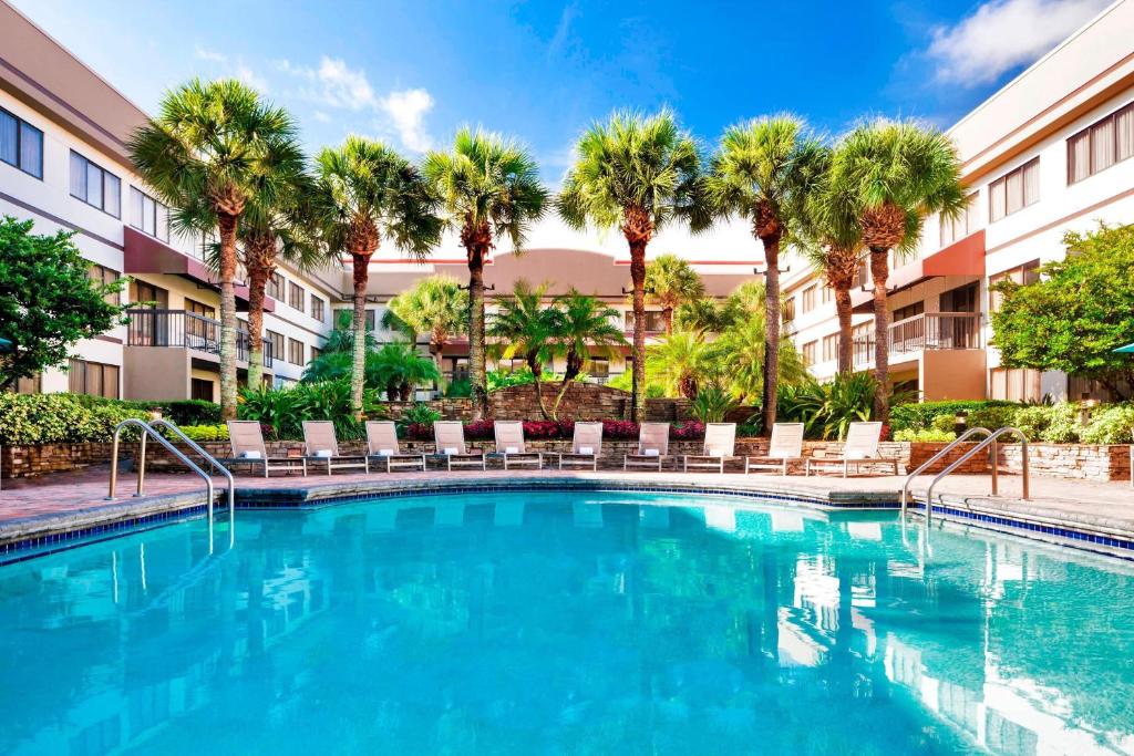 奥兰多奥兰多机场喜来登套房酒店的一座游泳池,里面种有椅子和棕榈树