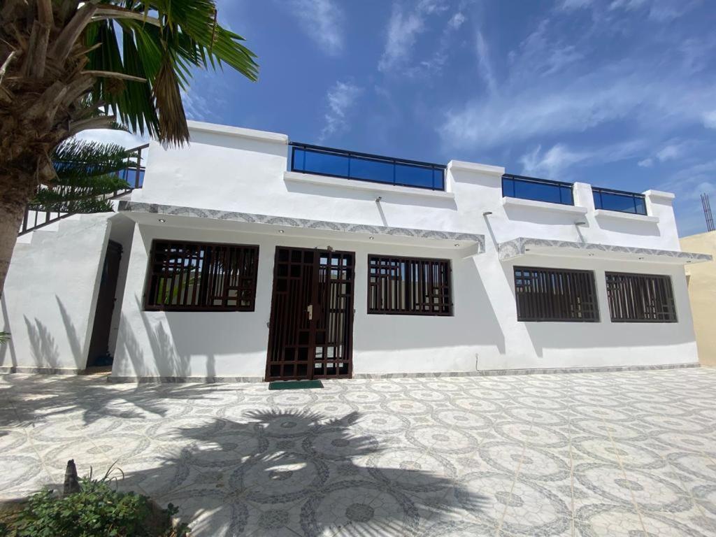 萨利波图尔Villa OMARI Situé à Saly Portudal Villa 2 Chambres bien équipés proche de tout的前面有棕榈树的白色房子