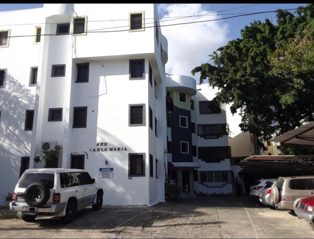 圣地亚哥洛斯卡巴Amplio y acogedor apartamento的前面有一辆汽车停放的白色建筑