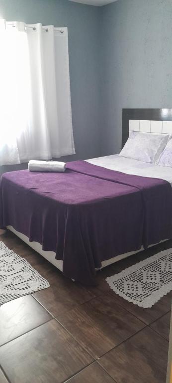 瓜鲁柳斯Meire Hostel的一间卧室配有一张带紫色毯子的床