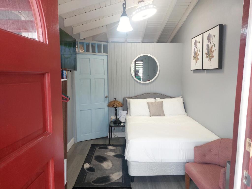 布里奇敦Carmen's Cozy Studio的卧室配有白色的床和红色的门