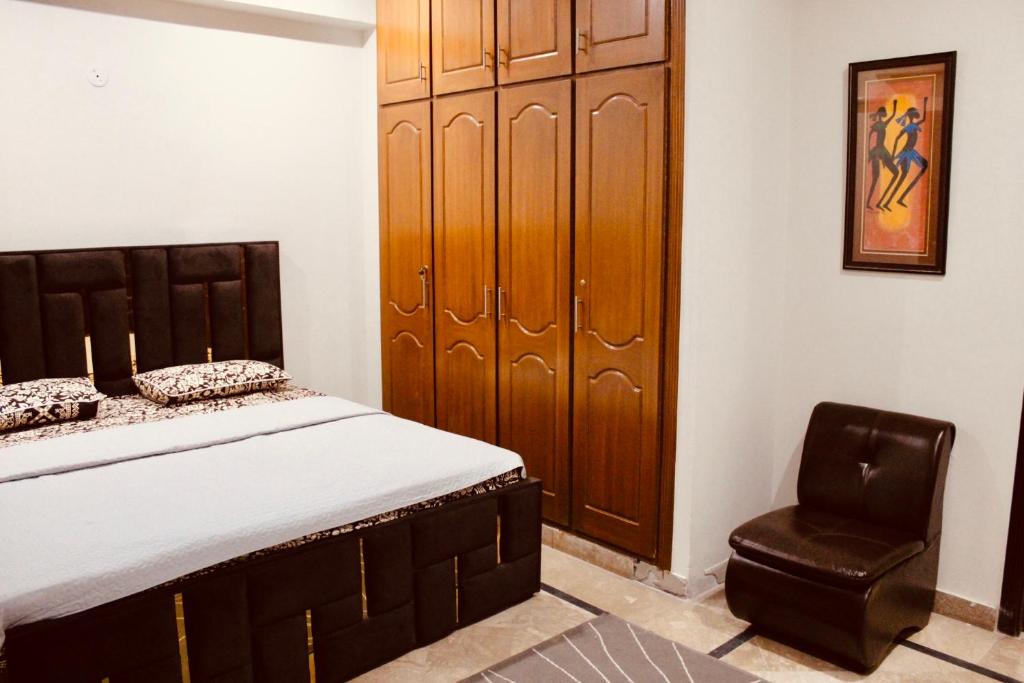 伊斯兰堡Islamabad Holiday Appartments One & Two Bed A Perfect Winter Escape to Murree, Northern Areas & Beyond的一间卧室配有一张床和一把椅子
