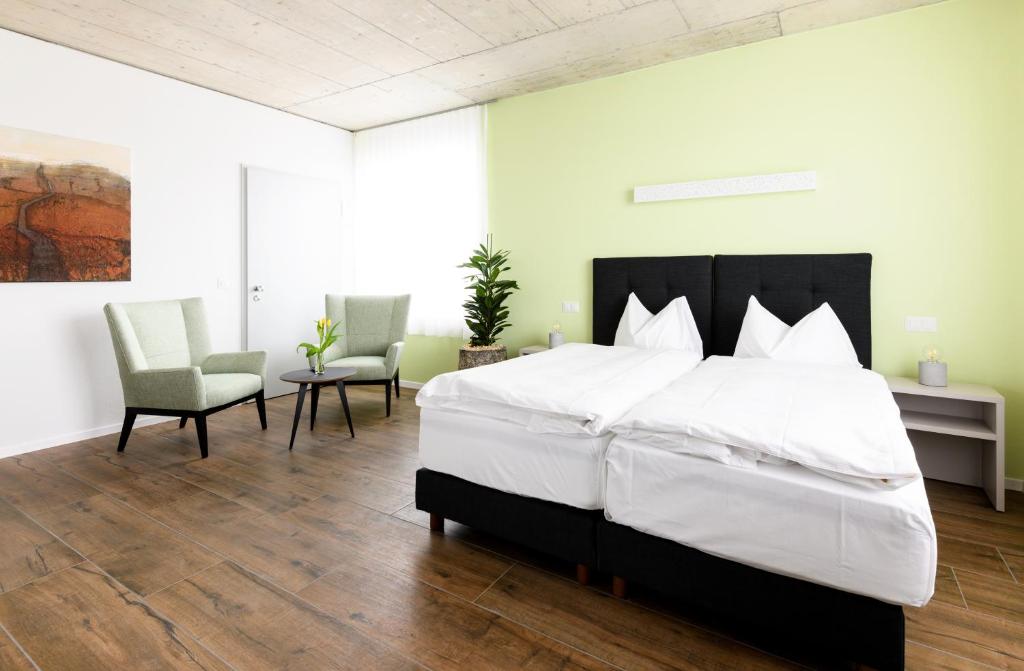 措芬根Partner Hotel AG Zofingen的一间卧室配有一张大床和两把椅子