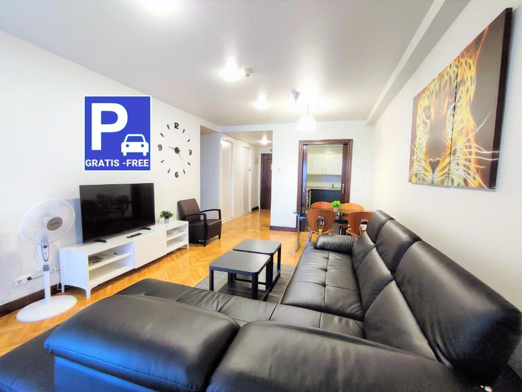 潘普洛纳Mendebaldea Suite Premium的客厅配有黑色真皮沙发和电视