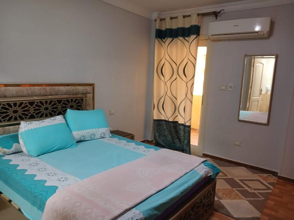 开罗compound city towers elwaha的一间卧室配有一张带蓝色床单和镜子的床
