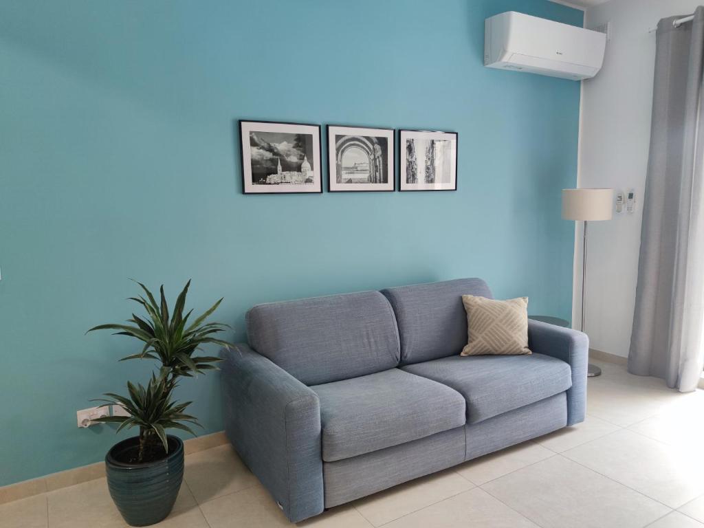 MġarrÉtoile Court Apt - homey, spacious & private patio的蓝色的客厅配有沙发和植物