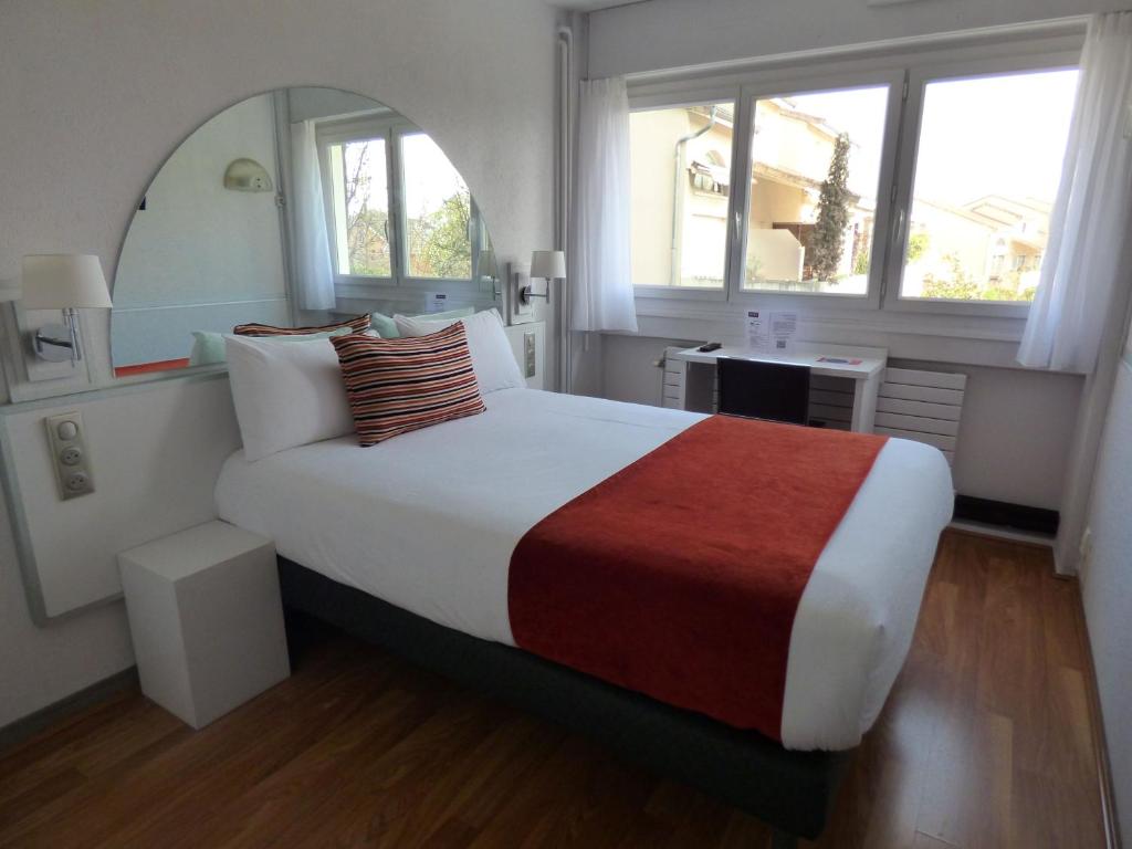 马孔Cit'Hotel Escatel的一间卧室配有一张大床和镜子