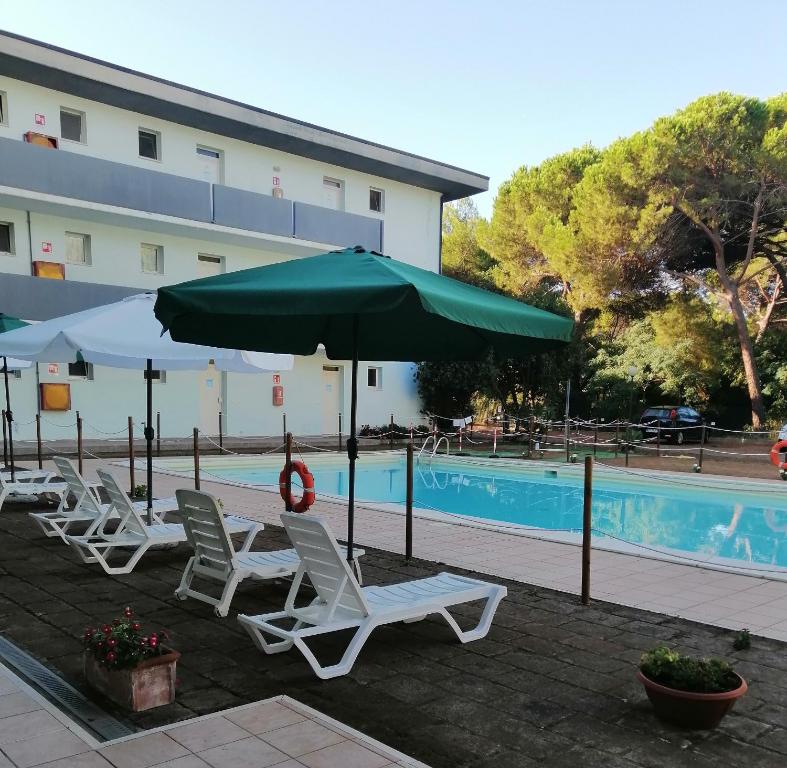 普林希匹纳马尔Residence Verde Pineta的一组椅子和一把遮阳伞,位于游泳池旁