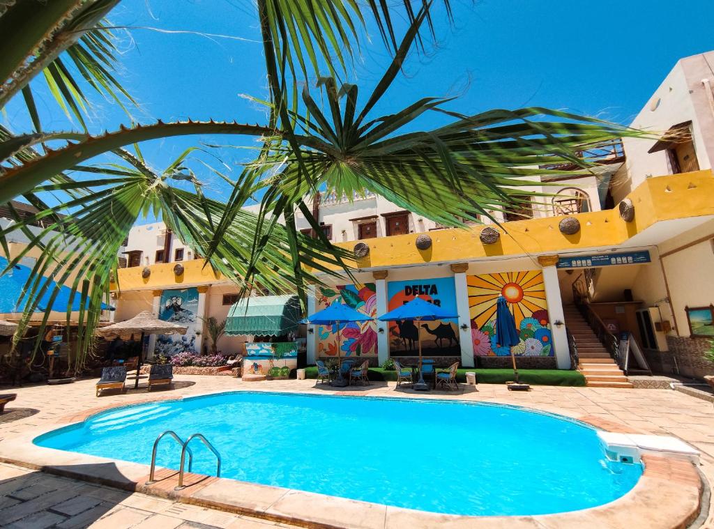 达哈布Delta Dahab Hotel的一座带游泳池的度假村,位于一座建筑前
