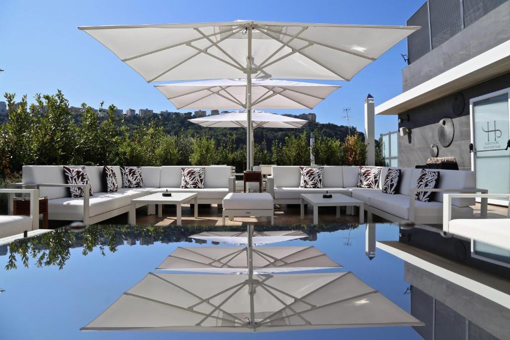 那不勒斯LHP Napoli Palace & SPA的一个带白色椅子和遮阳伞的庭院和一个游泳池