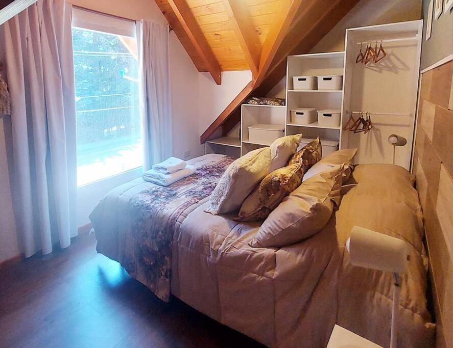 圣卡洛斯-德巴里洛切Amutuy Bariloche的卧室配有带枕头的床铺和窗户。