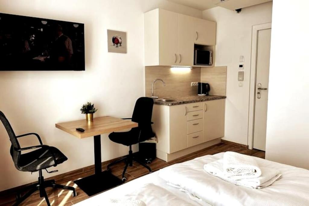 维也纳AJO Vetmed的一间带一张床和一张书桌的卧室和一间厨房