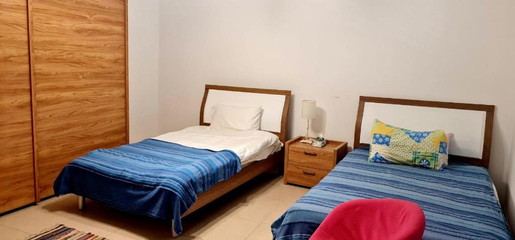 Al BurjFlat One Room Apartment Talabay Aqaba的一间卧室配有两张床和红色椅子