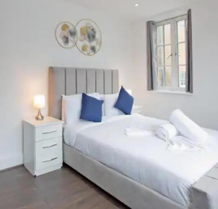 巴尔金Stylish Furnished Room In Barking Centre的卧室配有带蓝色枕头的大型白色床