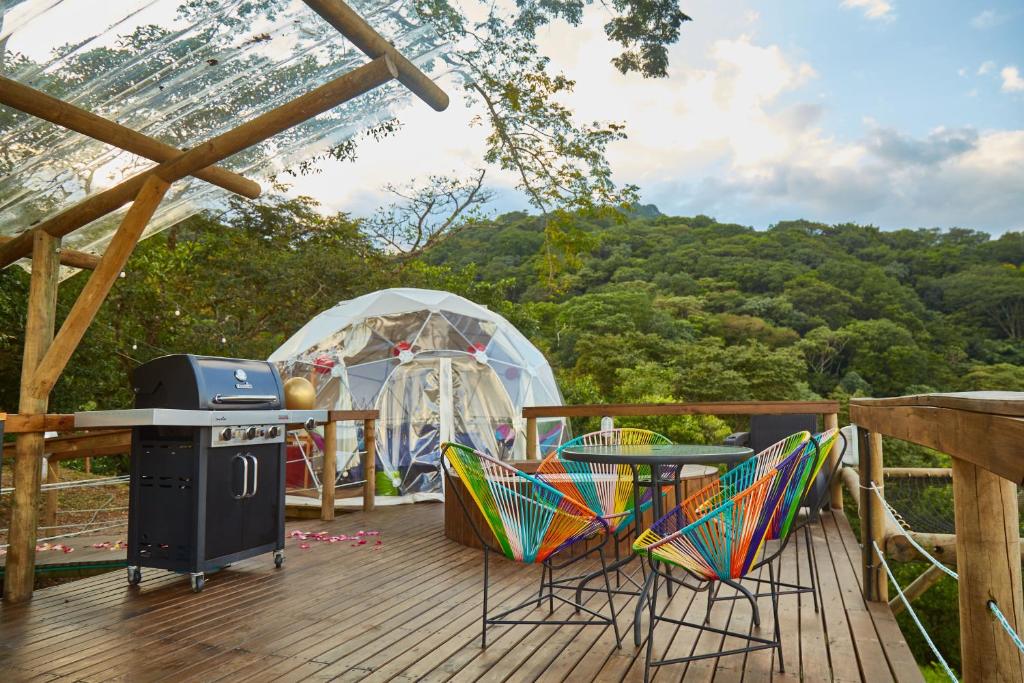 比亚维森西奥Glamping Itawa & Ecoparque turístico的一个带烧烤架和椅子的甲板和一个帐篷