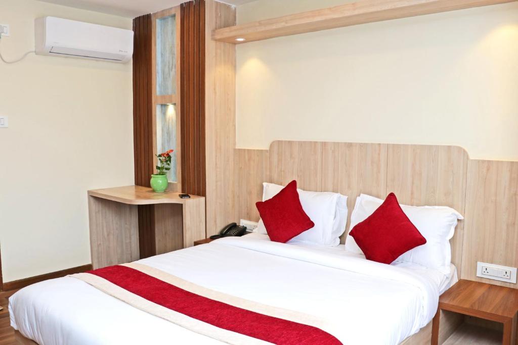 加德满都Hotel Nilakantha Pvt. Ltd的卧室配有带红色枕头的大型白色床
