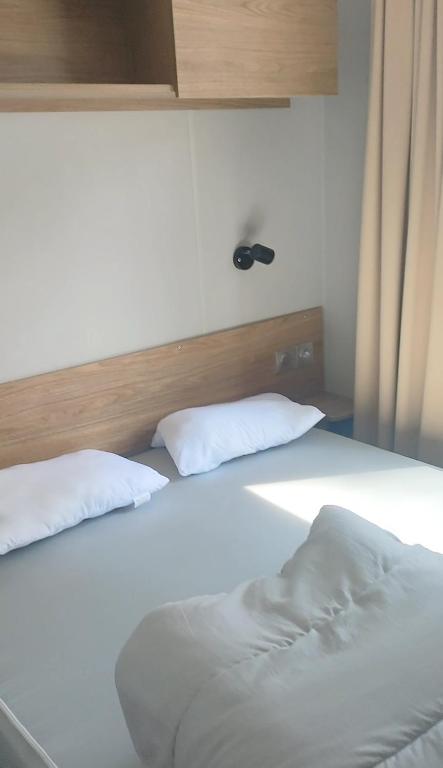 塞尼奥斯Mobil home spacieux的一张白色的床,上面有两个枕头