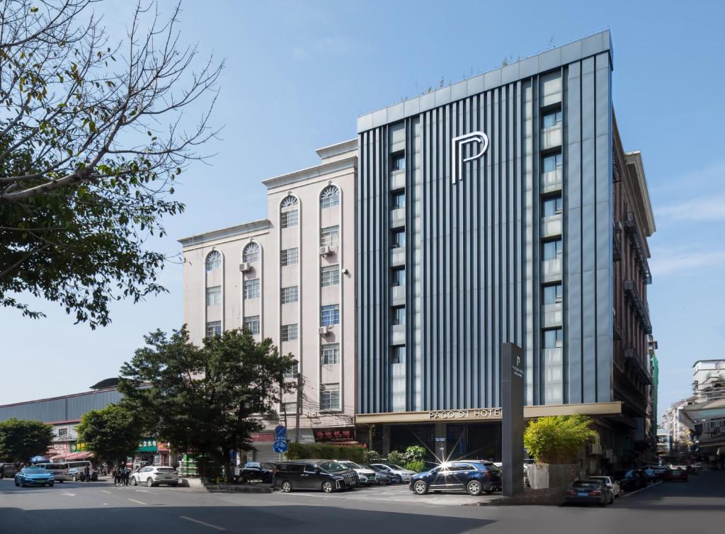 广州Paco Hotel Datang Metro Guangzhou的一座大型建筑,前面设有停车场