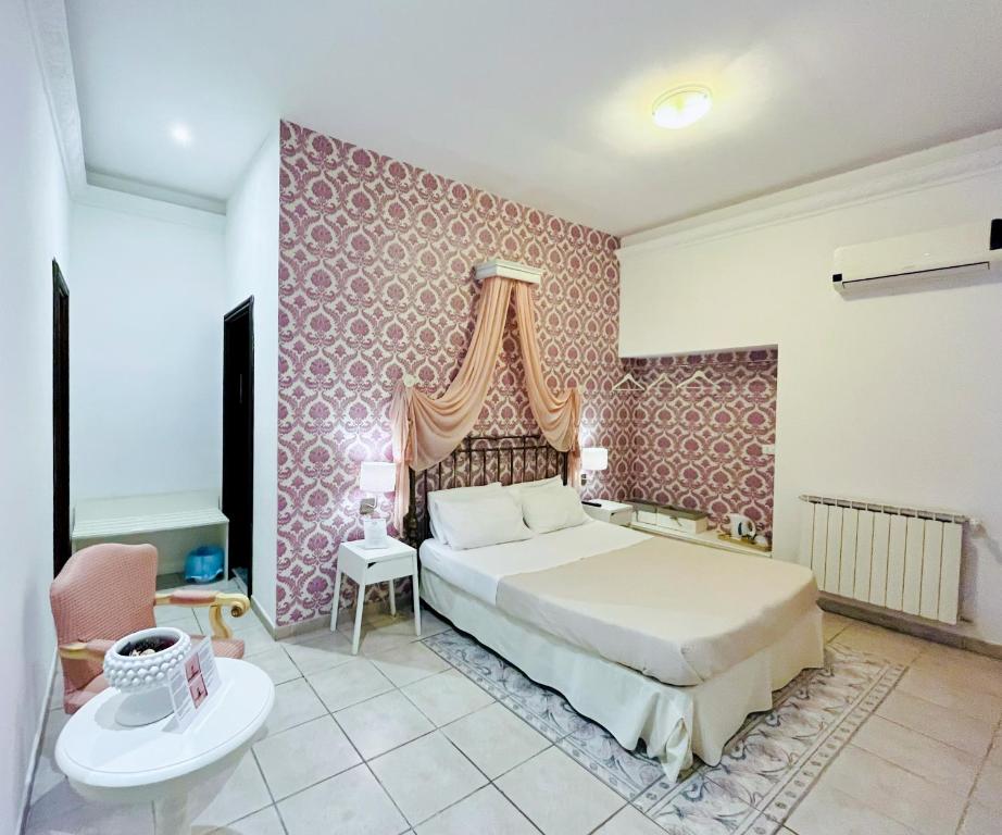 巴勒莫蒂卡巴勒莫住宿加早餐旅馆的一间卧室配有一张床和粉红色的墙壁